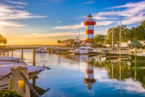 A scenic view of Harbour Town in Beaufort County, South Carolina, showcasing the famous lighthouse, boats, and marina under a clear sky.