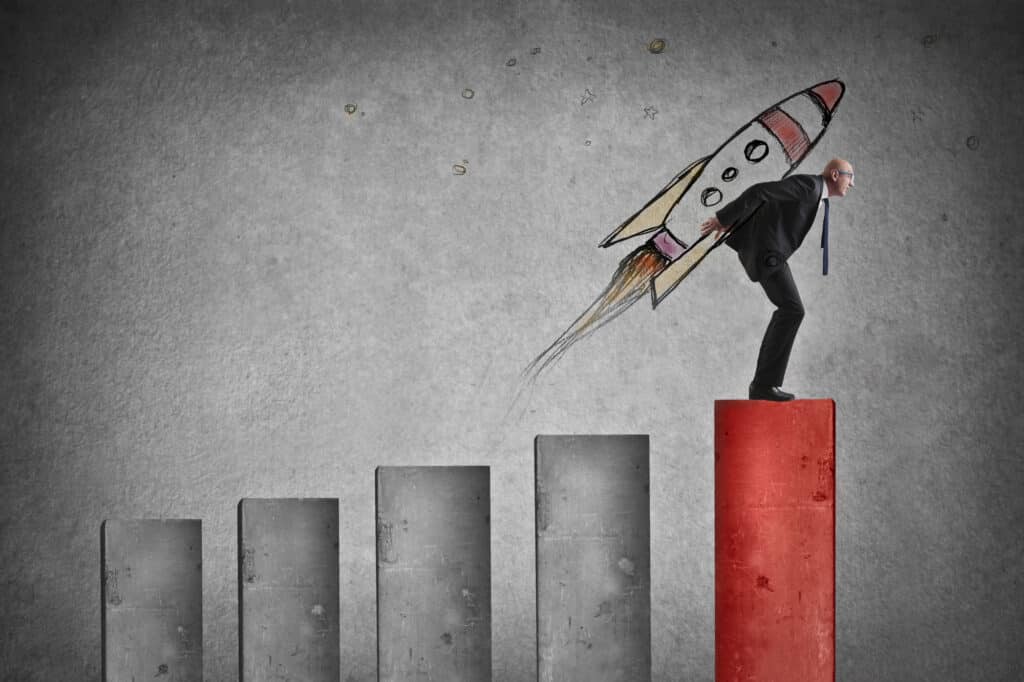 Businessman launching with a rocket from a bar graph to symbolize business growth and scaling.